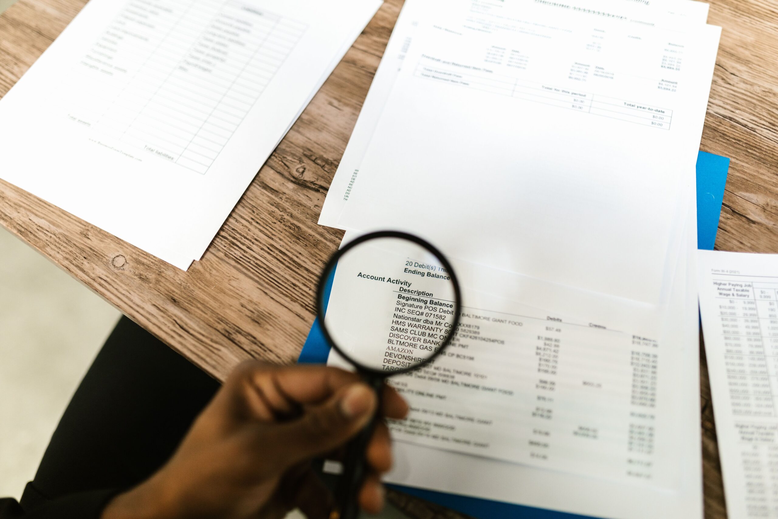 Hand holding a magnifying glass examining lines of text on a printed document