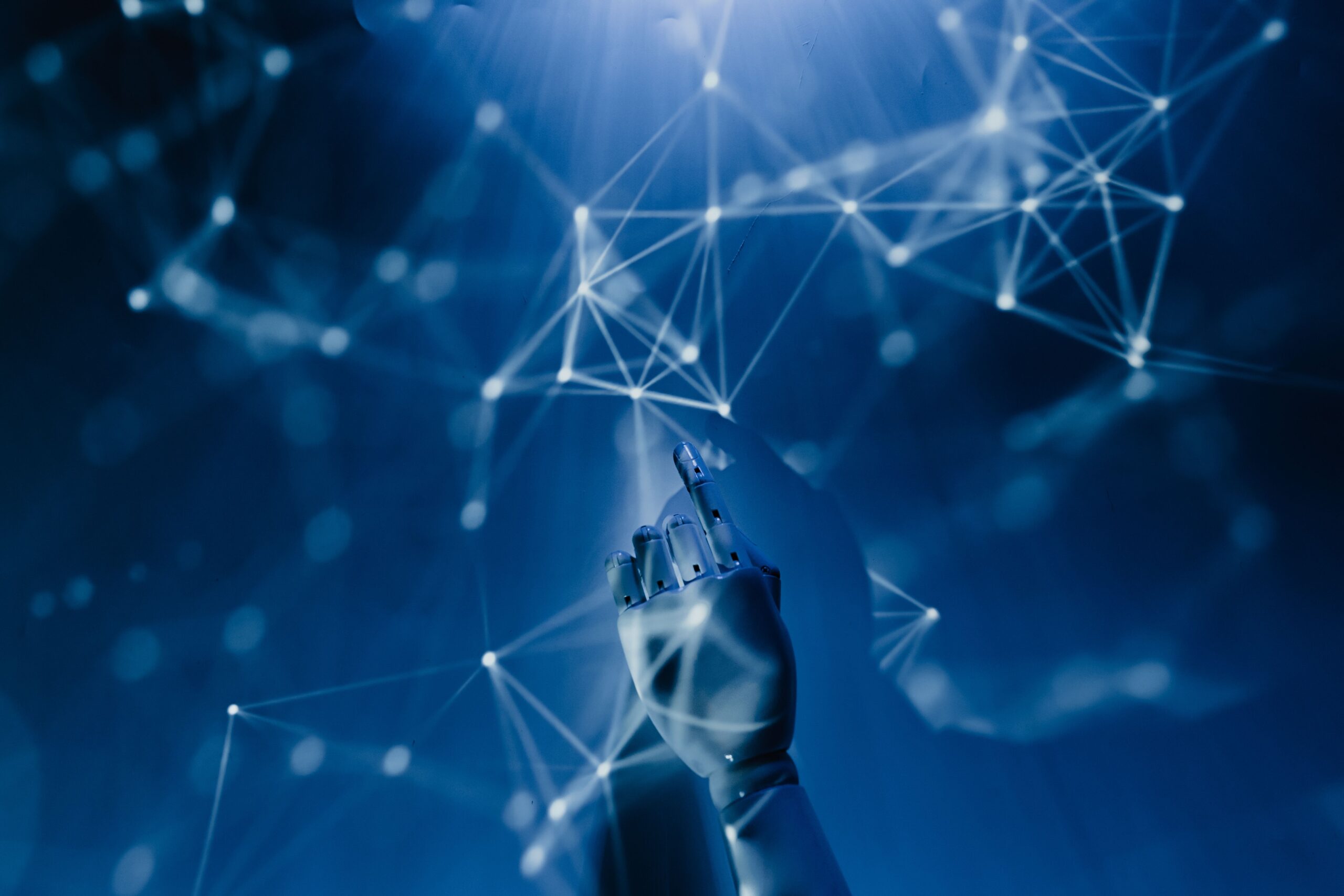Robotic hand reaching toward a glowing digital network on a blue background