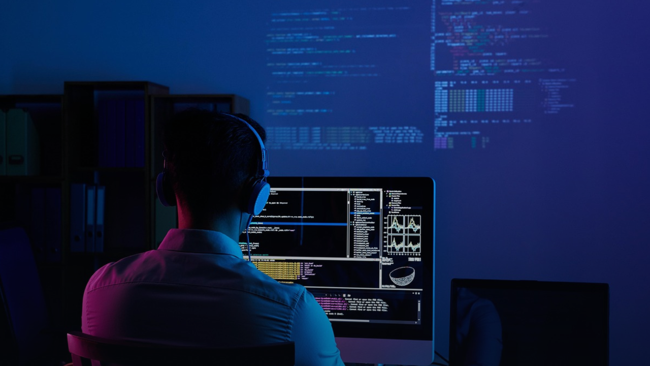 Developer working at a code-lit monitor, building software on AWS