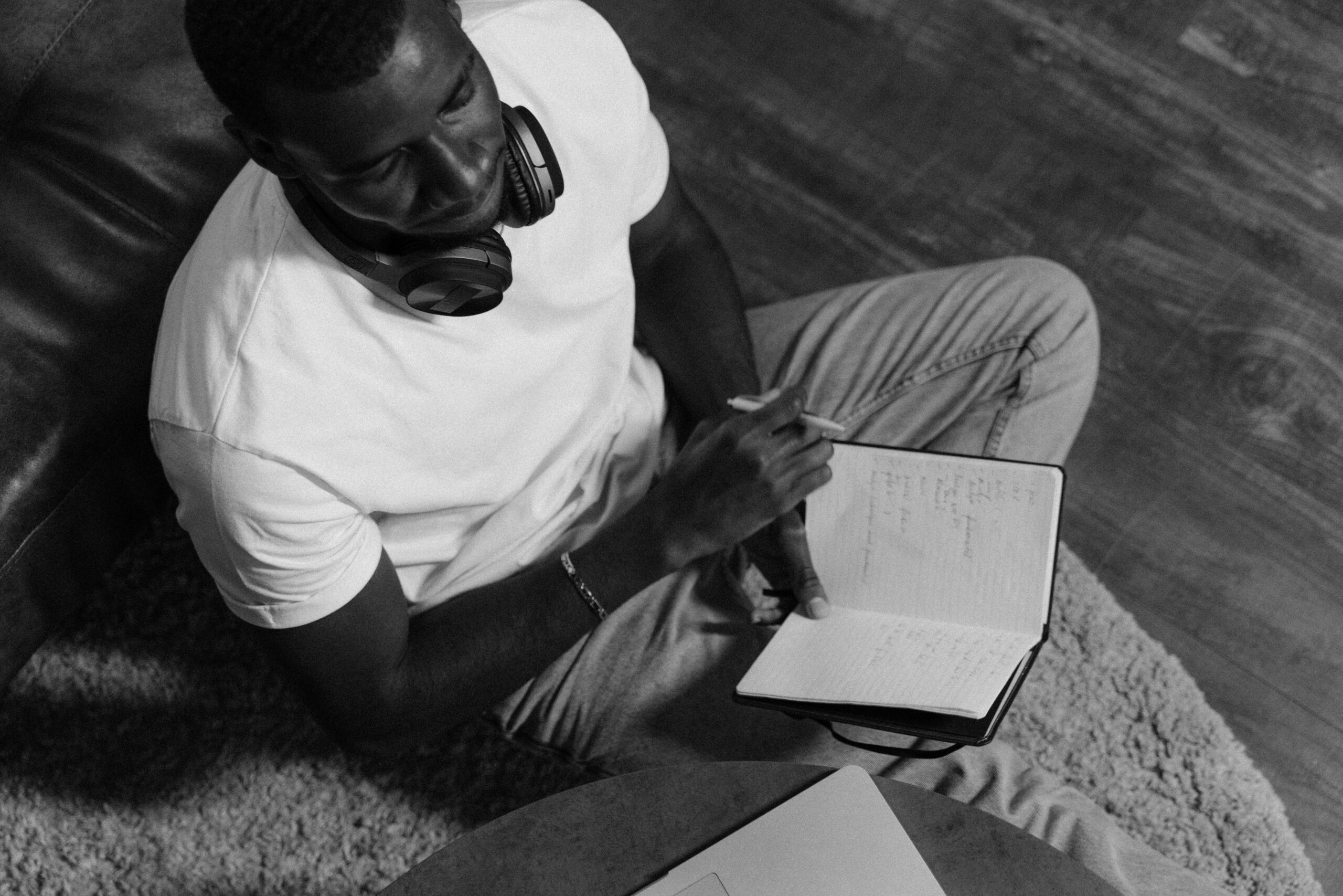 Person wearing headphones taking notes by hand while studying