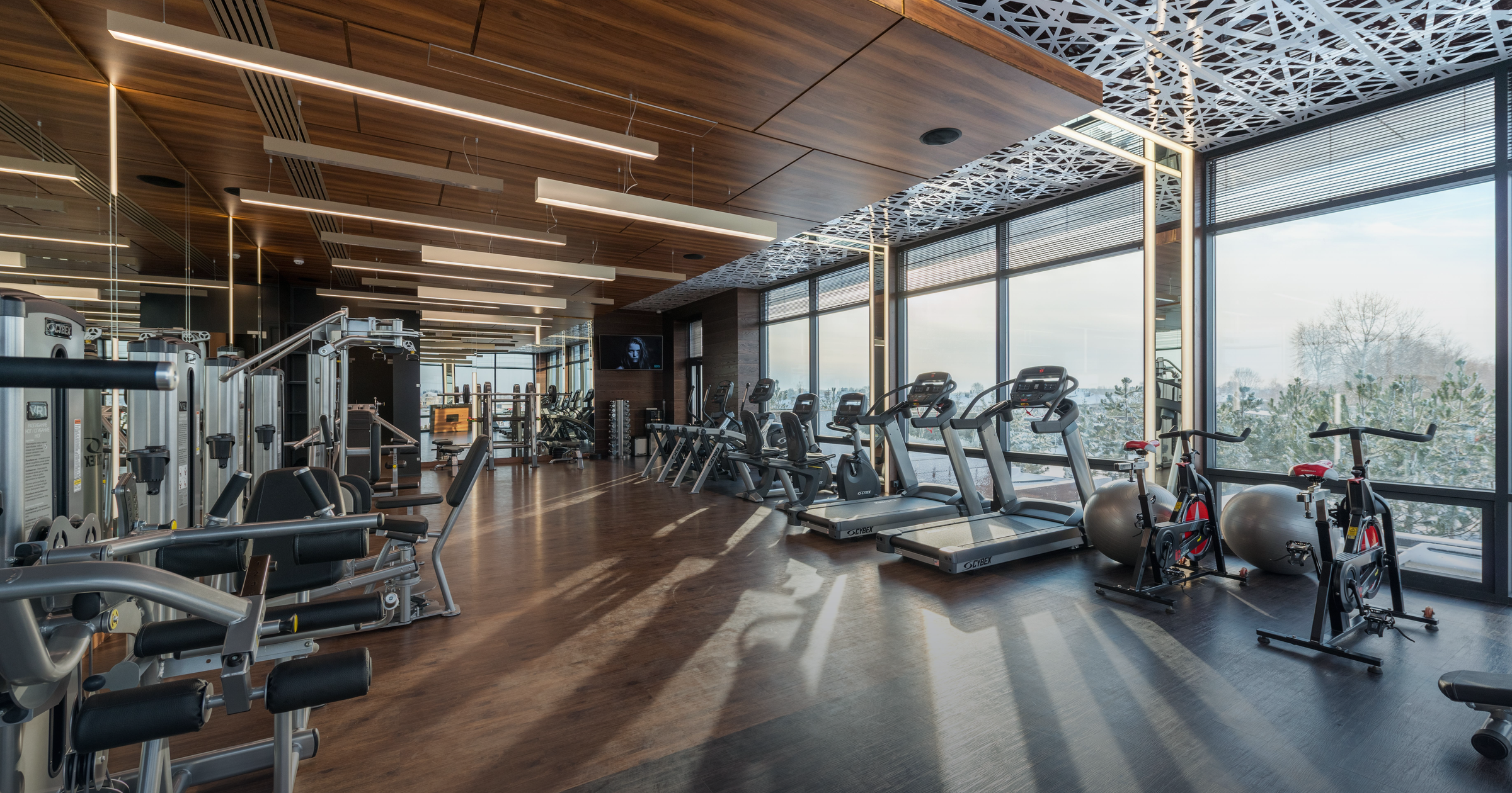 Modern 24-hour gym interior in Japan with cardio machines, weights, and a city-view window