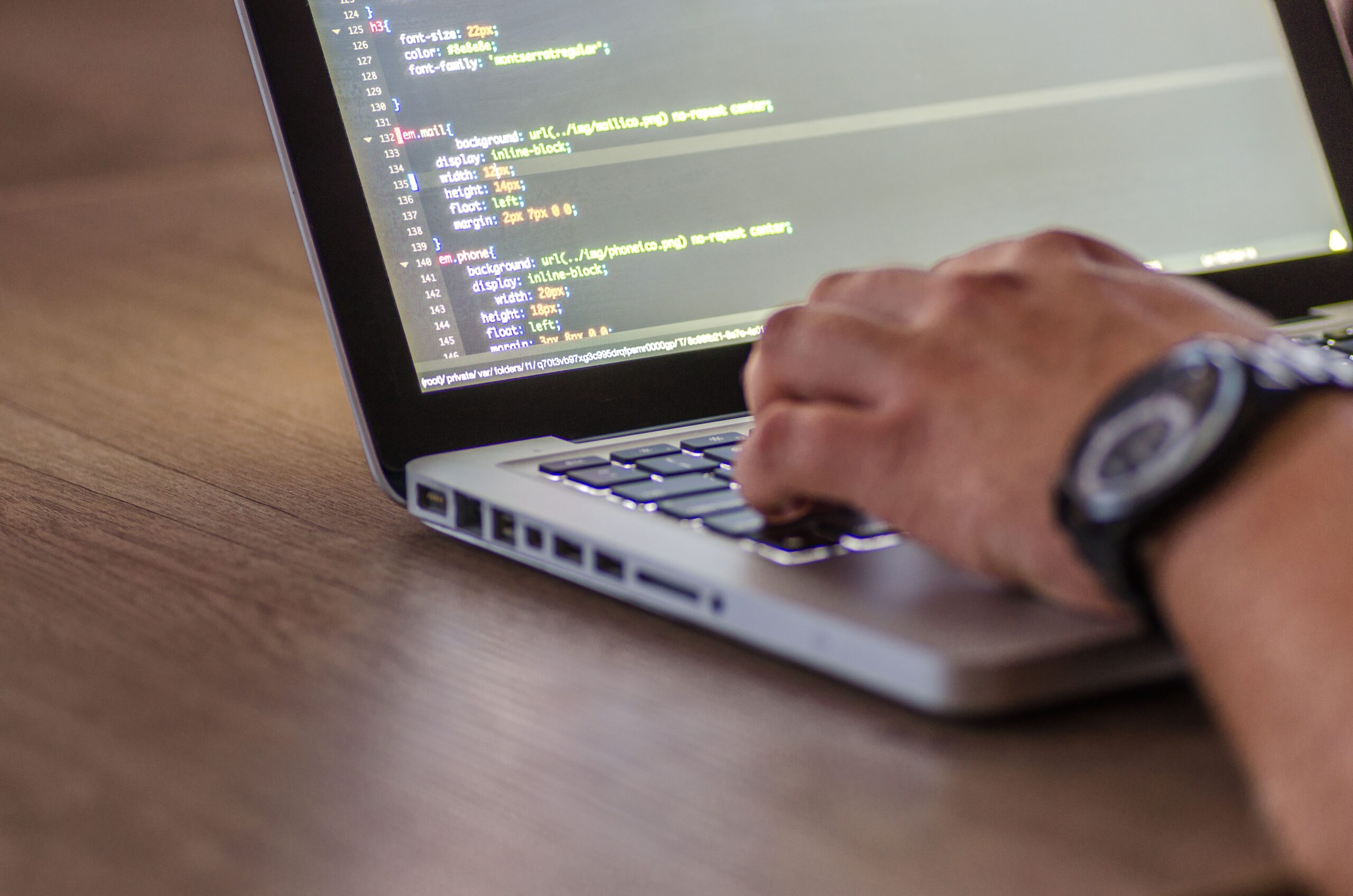 Developer's hands typing code on a laptop keyboard