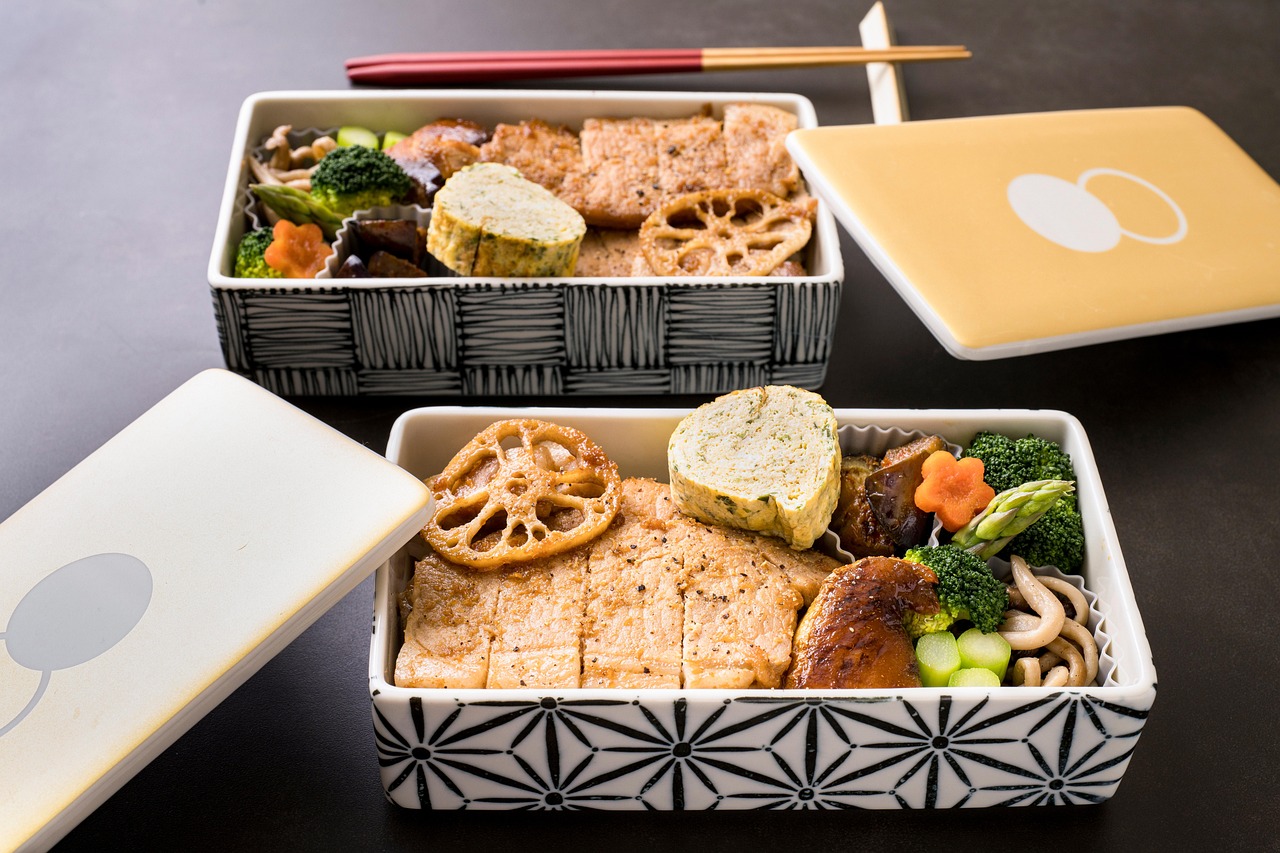 Two traditional Japanese bento boxes filled with regional dishes, illustrating furusato nozei return gifts