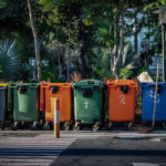 Row of color-coded recycling and waste bins along a street