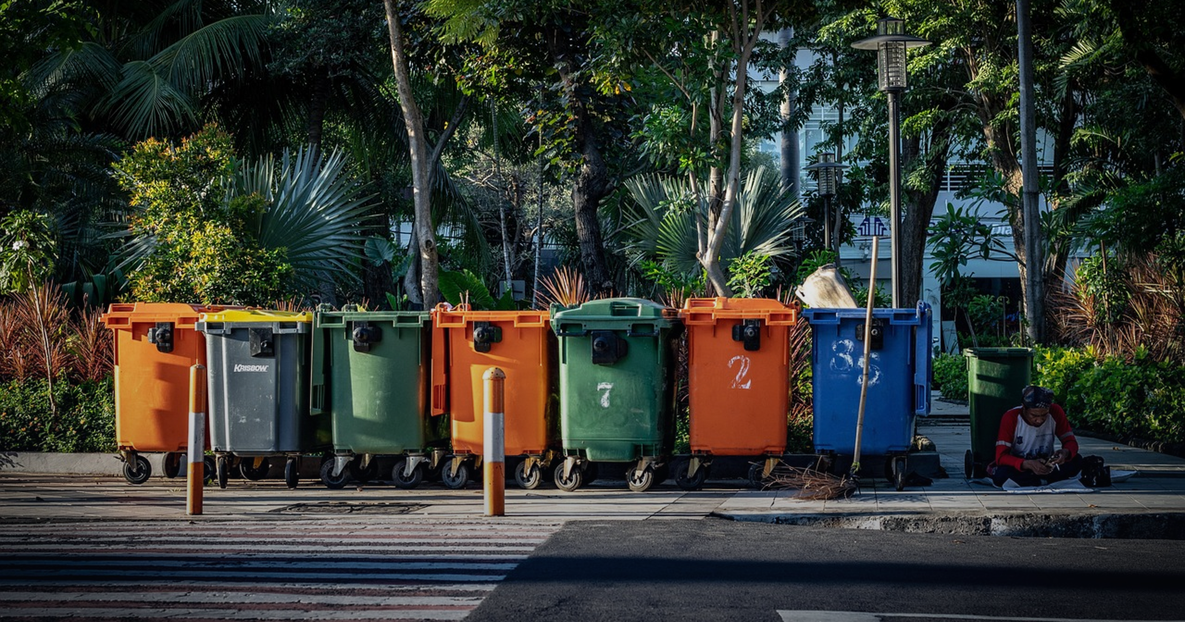 Row of color-coded recycling and waste bins along a street