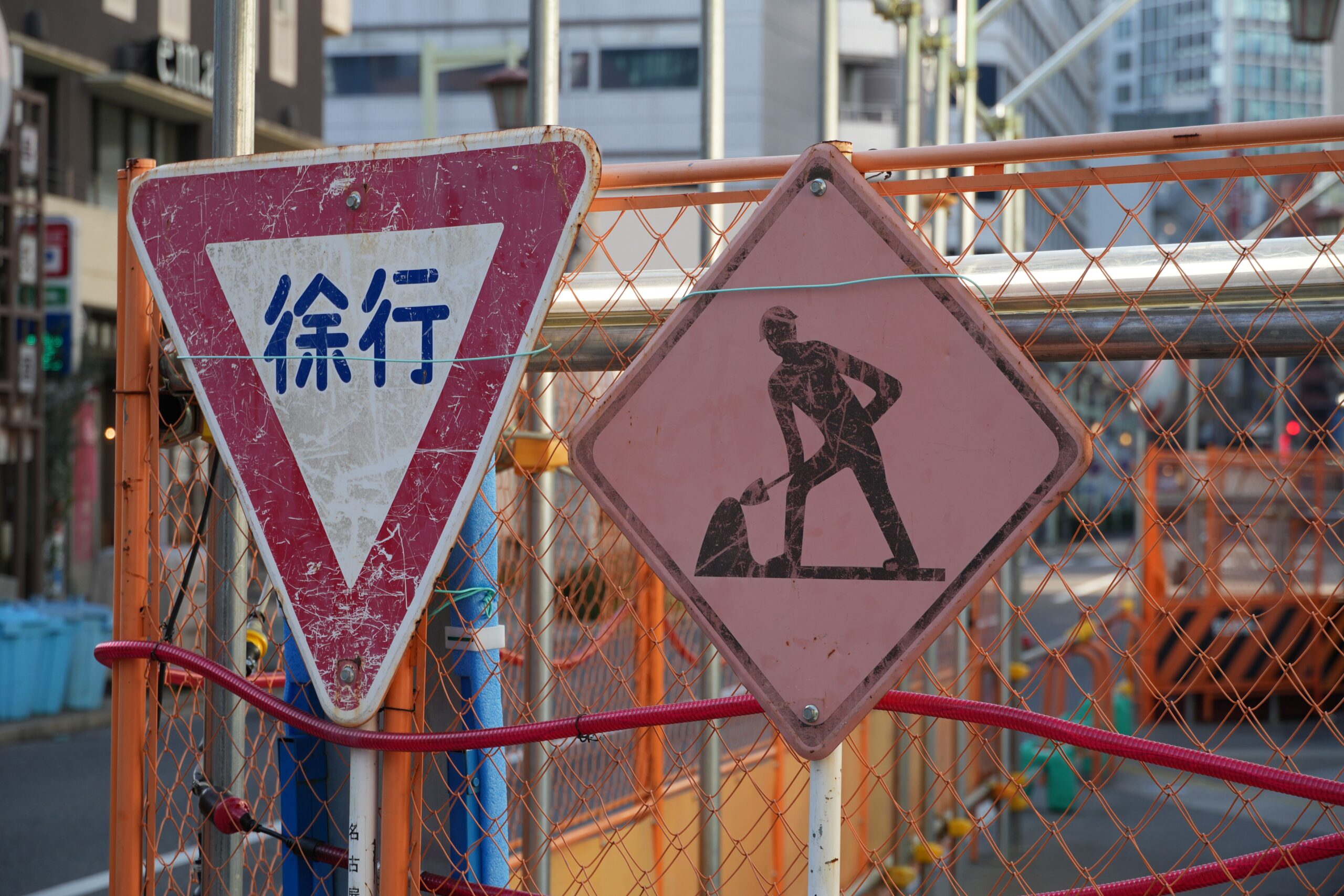 A construction site on a city street in Japan, marked with roadwork and slow-down (徐行) warning signs