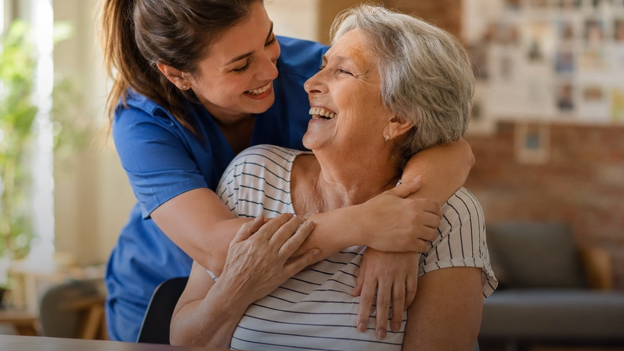 A caregiver embracing and supporting a smiling elderly woman