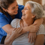 A caregiver embracing and supporting a smiling elderly woman