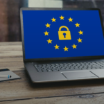 Laptop showing a padlock ringed by stars on a desk, symbolizing data privacy law