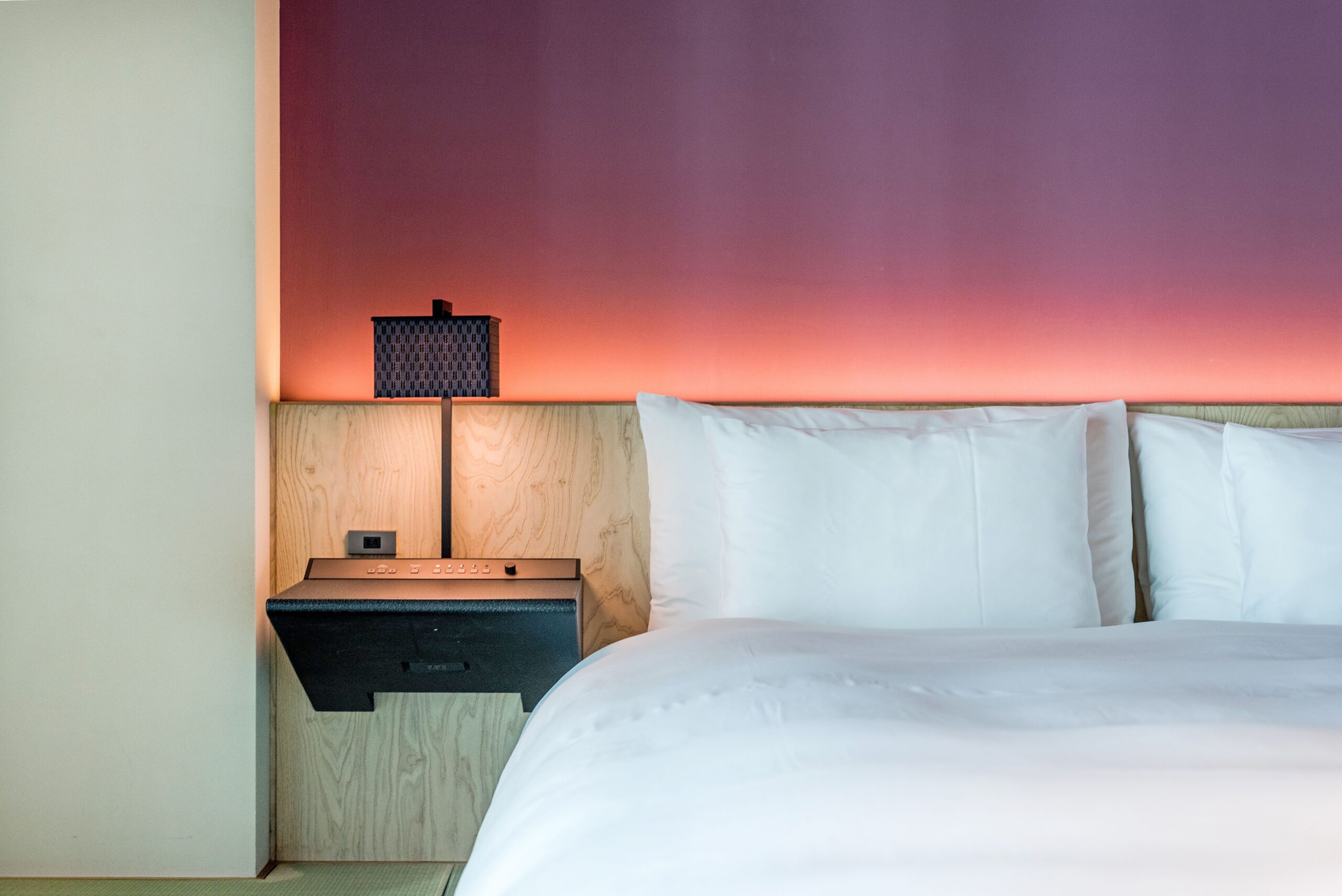 Modern, minimalist city hotel room with stylish lighting and crisp white bedding