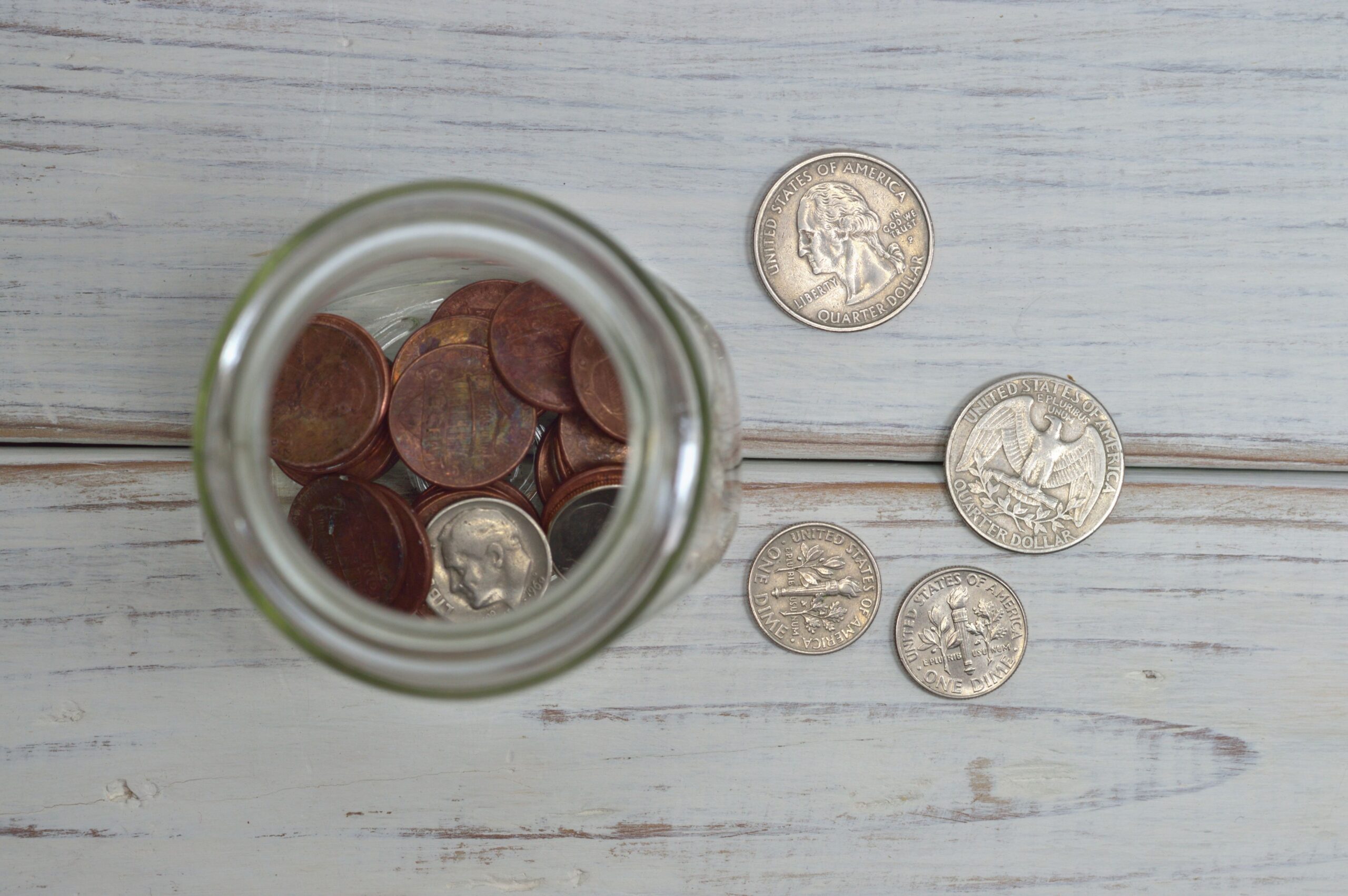 Coins in a glass jar on a wooden table symbolising long-term retirement savings