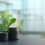 Green sprout growing from stacks of coins, symbolizing long-term investment growth