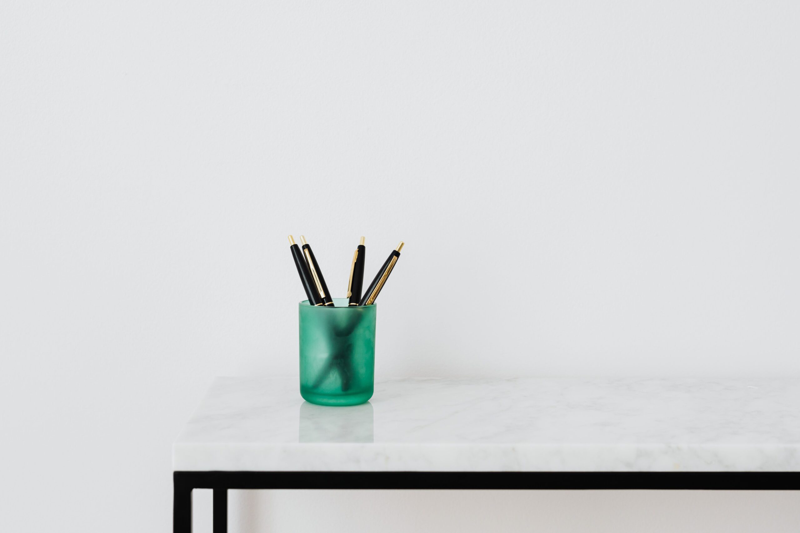 Minimalist desk with a green pen holder on a white marble table